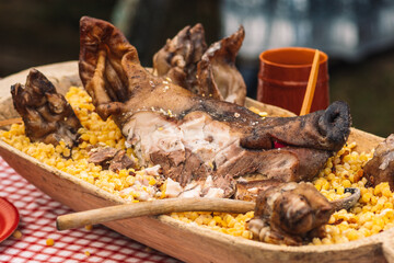 Grilled meat pork head in a wooden traditional plate on a table in a regional street market festival 