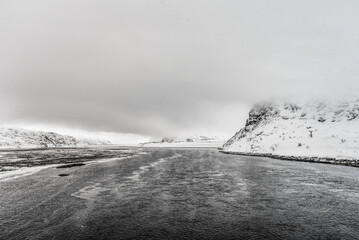 Snowy mountains hidden in the mist near the sea