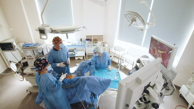 Surgeons team preforming operation in hospital operating theater, male surgeon operating patient,wearing surgical gown,operating room,,working with surgical laparoscopy instruments. Gynecology