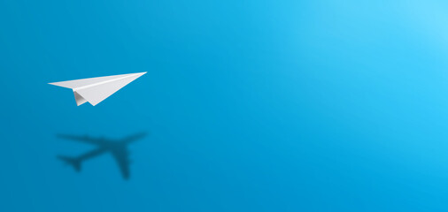 White paper plane casting shadow of airplane on blue background. Concept for travel, business idea,...
