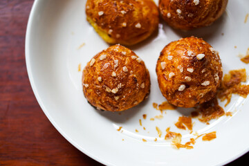 chouquette cream puffs on white plate. wood background