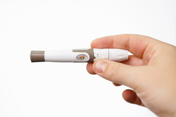 Close up photo of human hand holding a lancet for checking blood sugar level by glucose meter, diabetes concept.