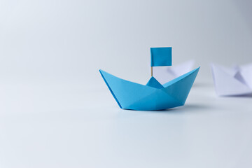 Leadership and teamwork, Blue leader paper ship leading hind white on white background.