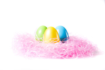 Green Yellow and Blue Plastic Easter Eggs Nesting on Pink Grass on a White Background