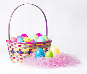 Bunch of Colorful Plast Easter Eggs in a Festive Multi-color Wicker Basket with Handle and Pink Grass