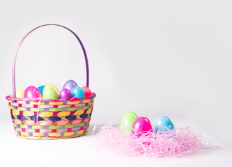 Bunch of Colorful Plast Easter Eggs in a Festive Multi-color Wicker Basket with Handle and Pink Grass
