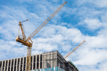 Modern building and tower crane in construction site with blue sky background. Construction...