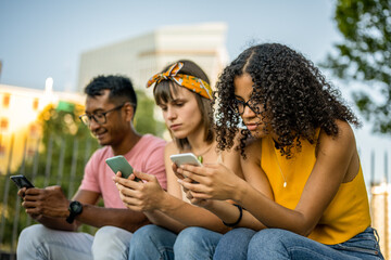 Three young people looking at cell phone, diverse friends spending time on social media, generation...