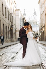 Naklejka premium An international wedding couple, a European bride and an Asian groom walk around the city together.