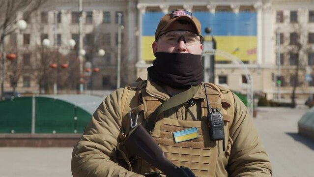 Unrecognizable male soldier in sunglasses aiming weapon while fighting in war in countryside
