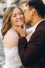 An international wedding couple, a European bride and an Asian groom walk around the city together.