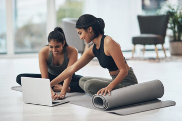 Lets start our virtual session. Shot of two young women using a laptop while working out at home.