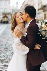 Naklejka premium An international wedding couple, a European bride and an Asian groom walk around the city together.