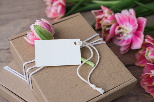 Mock up tag and kraft gift boxes decorated with flowers. Preparation of gifts for mother's day, birthday, women's holiday. Gift wrapping idea