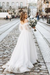 Beautiful bride with a bouquet posing in the city streets