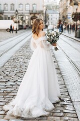Obraz premium Beautiful bride with a bouquet posing in the city streets