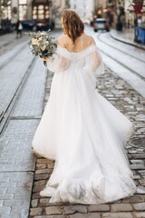 Fototapeta na wymiar Beautiful bride with a bouquet posing in the city streets