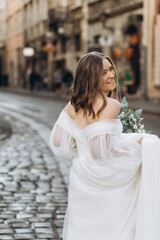 Beautiful bride with a bouquet posing in the city streets