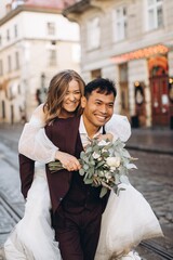 An international wedding couple, a European bride and an Asian groom walk around the city together.