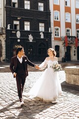 An international wedding couple, a European bride and an Asian groom walk around the city together.