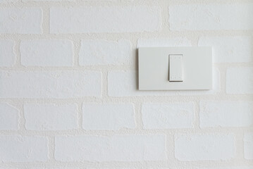 Single white electrical light switch on white wallpaper background. Save energy and home decoration concept.