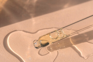 close up of pipette with pouring liquid serum and shadows