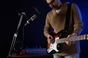 Obraz premium Man singing and playing guitar. Musician in record studio holding acoustic guitar