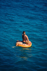 A man floats on an inflatable ring in the sea with blue water. Vacation at the sea on a sunny day. Turkey vacation concept. Selective focus