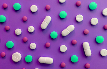 Background of multi-colored pills on a purple background.