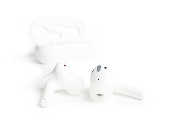 Closeup abstract white TWS (true wireless stereo) earbuds isolated on white background. Shallow focus.