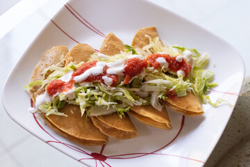 Tacos dorados con salsa, lechuga y crema