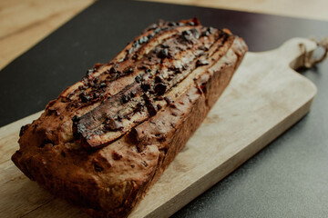Banana cake with dark chocolate and nuts on a mango tree board