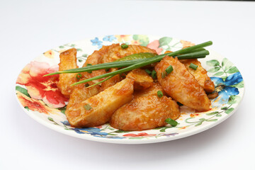 Honey Chilli Potato or Schezwan Aloo in black bowl on dark slate table top. Chilli Potatoes is indo-chinese cuisine dish. Authentic asian food. Indian meal
