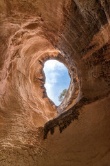 Big orange rock cave. A cave where the ancestors lived. An ancient cave. Natural window made of stone. eroded cave