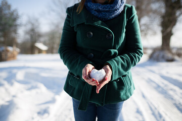kobieta trzyma serce ze śniegu w dłoniach - obrazy, fototapety, plakaty