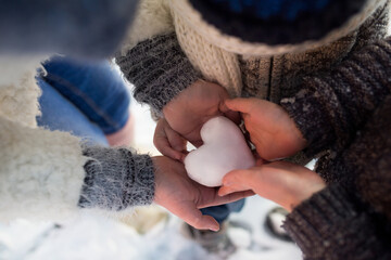 dzieci trzymają śnieżne serce w dłoniach