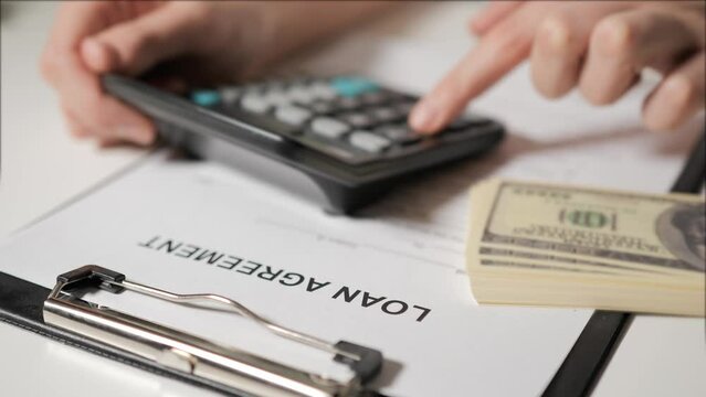 loan agreement. The hands of a banker woman calculate the loan terms, repayment terms and monthly payment on a calculator. A woman borrows money, a credit card.