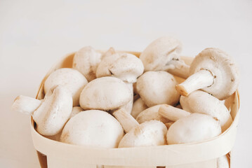 Champignon mushrooms in a wicker basket on a white background