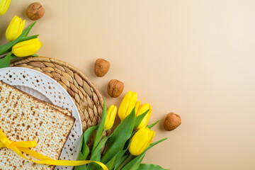 Matzah, seder plate and yellow tulip flowers on modern background with copy space. Passover...
