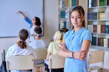Obraz premium Female teenager student smiling looking at camera, group of pupils and teacher students in library