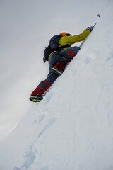 Alpine climber, climbing snow slope during winter mountain ascent.