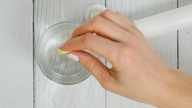 hand holds yellow effervescent soluble tablet and places it in glass of water. Concept of treatment and prevention of viral diseases. Help for depression and insomnia. white background. slow motion.
