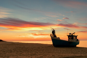 Fishing boat standing on beach during beautiful sunset at seashore