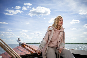 Fototapeta premium Young woman navigating sailboat sails on the lake
