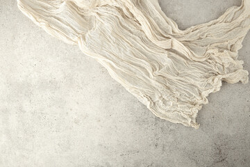 Wrinkled gauze fabric on light grunge stone background. Cotton gauze fabric cloth on stone tile...