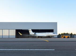 Luxury business jet is being towed out of the hangar - obrazy, fototapety, plakaty