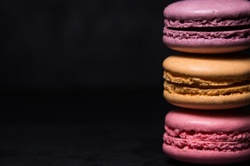 Colored macarons on a black background. Light and tasty dessert. traditional dessert