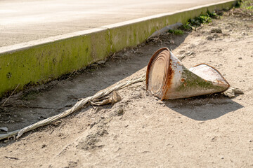 Shallow focus of an industrial oil drum seen crushed and discarded at the side of a road at an oil refinery. Seen at the  kerbside new the refinery entrance.