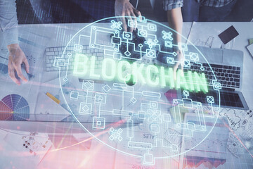 Double exposure of man and woman working together and crypto finance theme hologram. Blockchain...