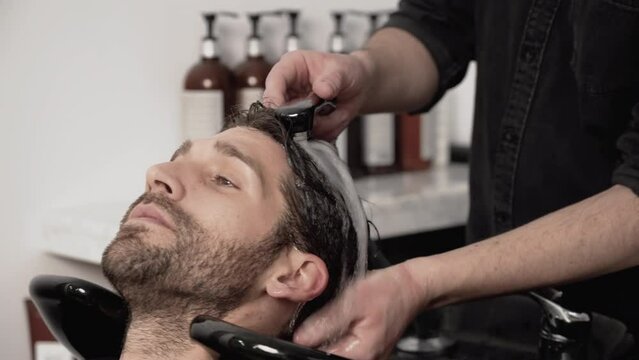 Barber shop. Hairdresser man washes client head in barbershop. High quality 4k footage